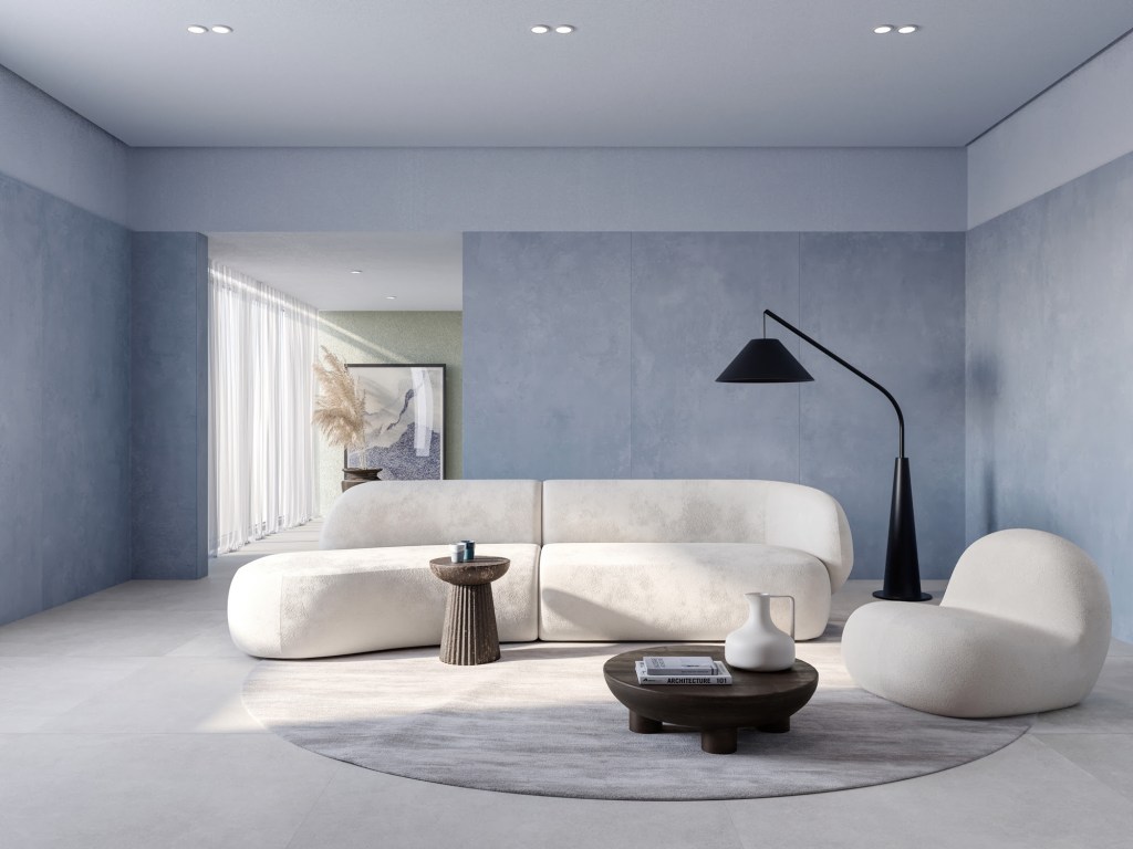 Foto mostra sala de estar minimalista com sofá e poltrona brancos e com design orgânico, tapete felpudo redondo, luminária preta de chão.
