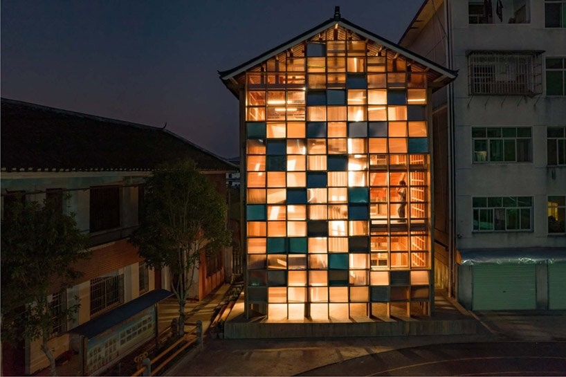 Vista noturna da fachada de biblioteca com fachada luminosa formada por estantes de livros.