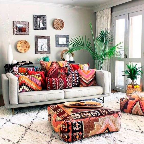 Sala em estilo Boho com sofá com almofadas coloridas e pufe colorido como mesa de centro