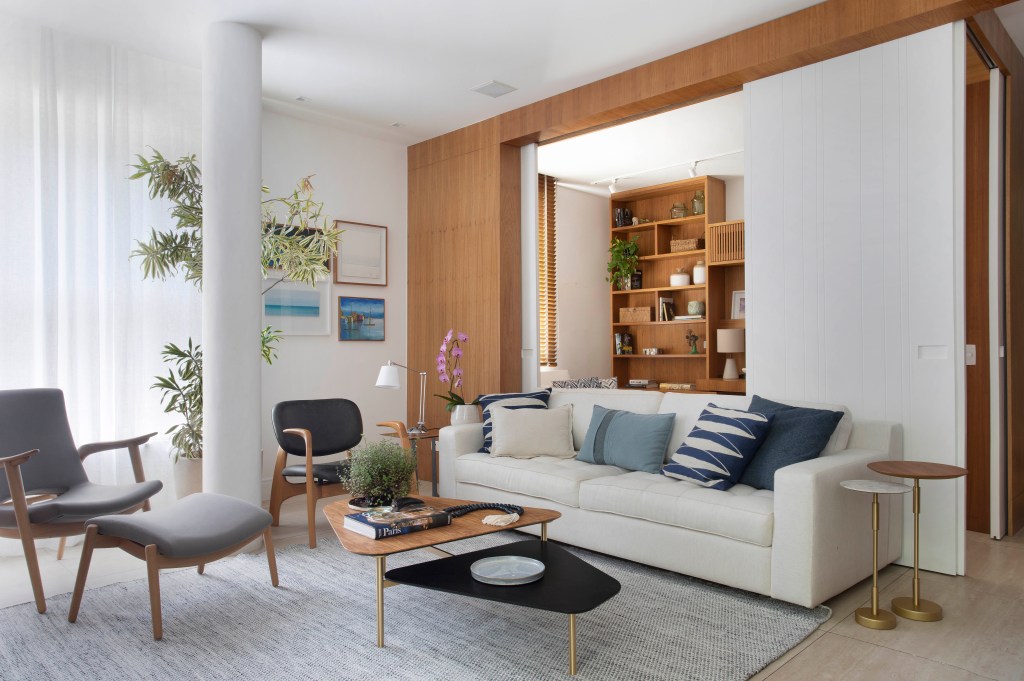 Sala de estar com painel de madeira e sofá branco
