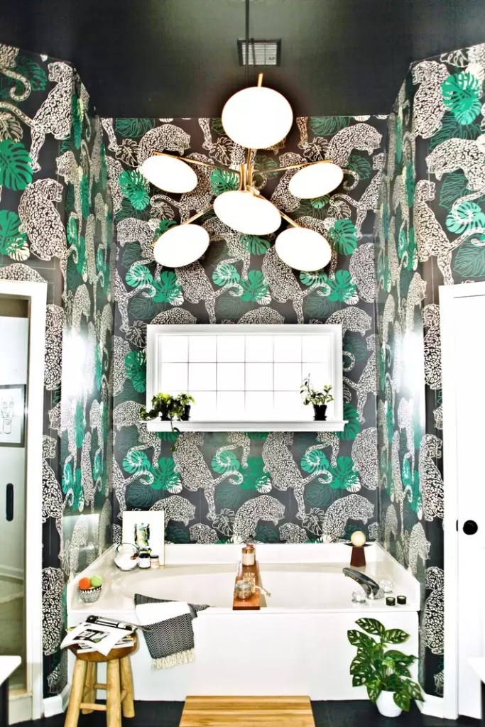 12 ideias fofas para decorar o banheiro-Laquita Tate Banheiro com paredes e teto revestidos por papel de parede com padrão de leopardos e folhas de costelas de adão sobre fundo preto.