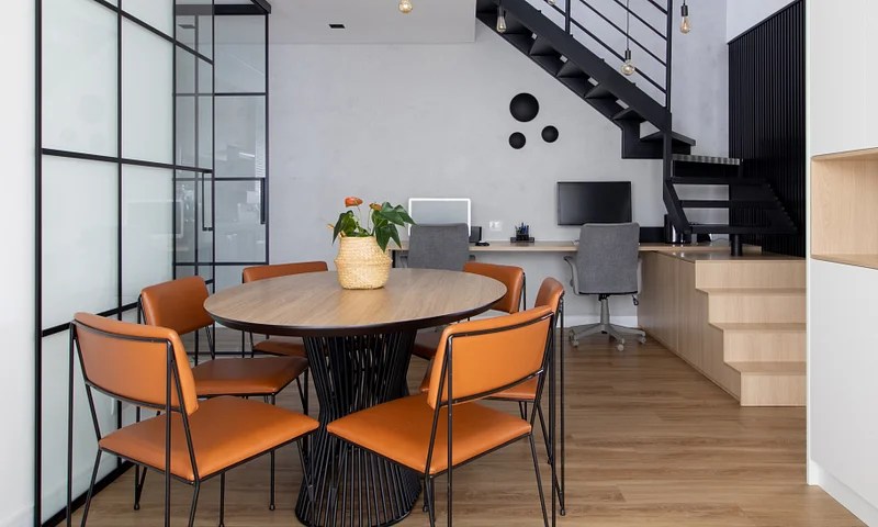 Sala de jantar com mesa redonda em madeira; cadeiras laranjas