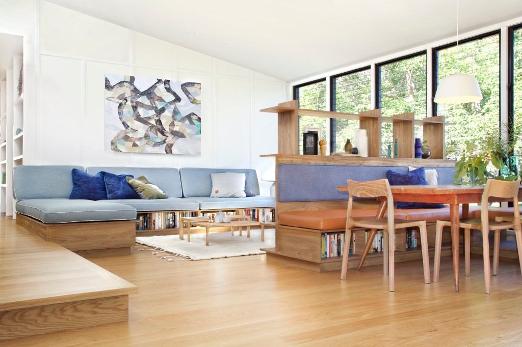 Sala de estar integrada com sala de jantar, piso de madeira, sofá em L com almofadas coloridas
