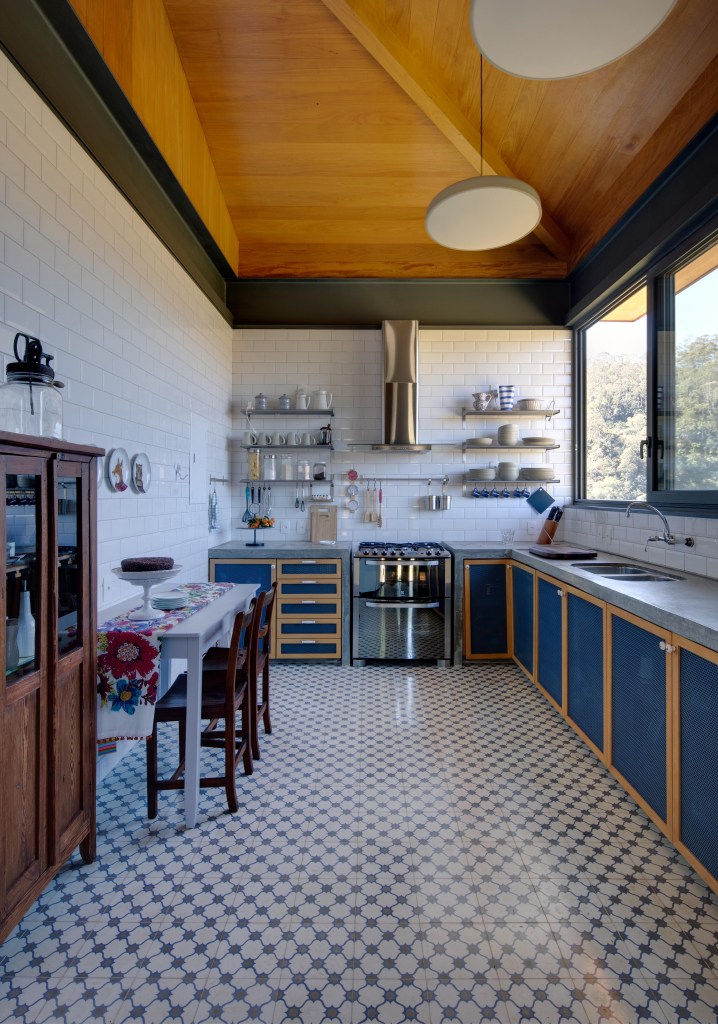 Cozinha de casa de campo com piso branco, marcenaria azul e madeira