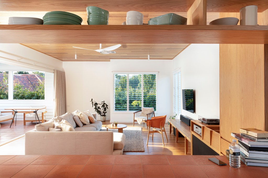 Sala de estar com janela para paisagem natural, sofá branco e móveis de madeira