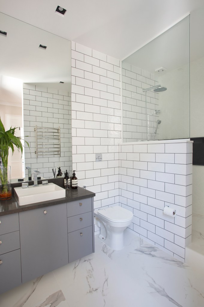 Banheiro com tijolinhos brancos e armário cinza