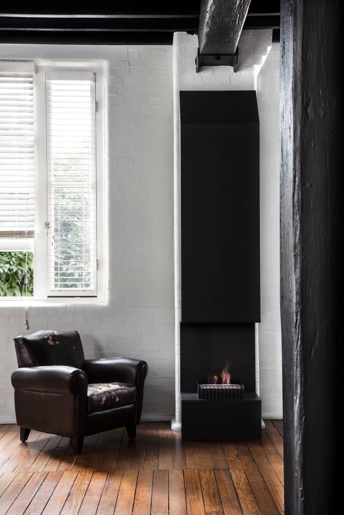 Sala de estar com painel preto, poltrona de couro e grande janela