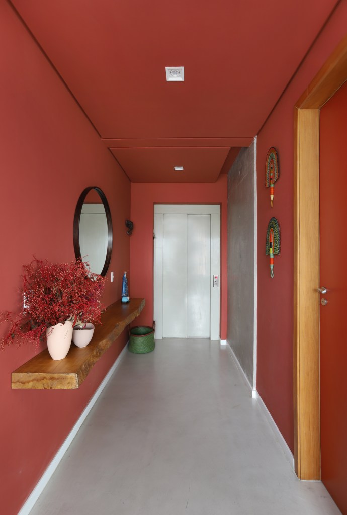 Hall de entrada vermelho com espelho redondo