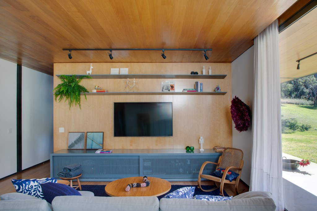 Sala de TV com cadeira de balanço e painel de madeira