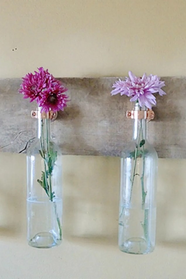Traga seu jardim para dentro colocando flores em uma vitrine de garrafas penduradas.