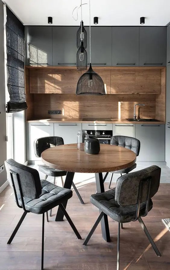 Mesa redonda de quatro lugares em primeiro plano em uma cozinha. Cores em preto e amadeirado.