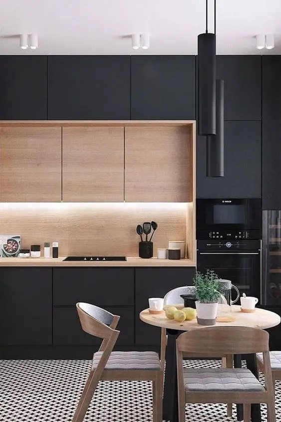 Espaço de jantar integrado a cozinha. Ao fundo, armários embutidos pretos com bancada em madeira de cor clara.