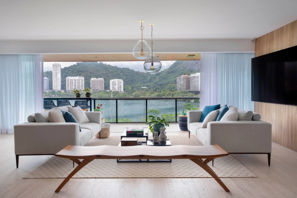 Sala de estar com vista para Lagoa com mesa de centro de madeira e sofá branco