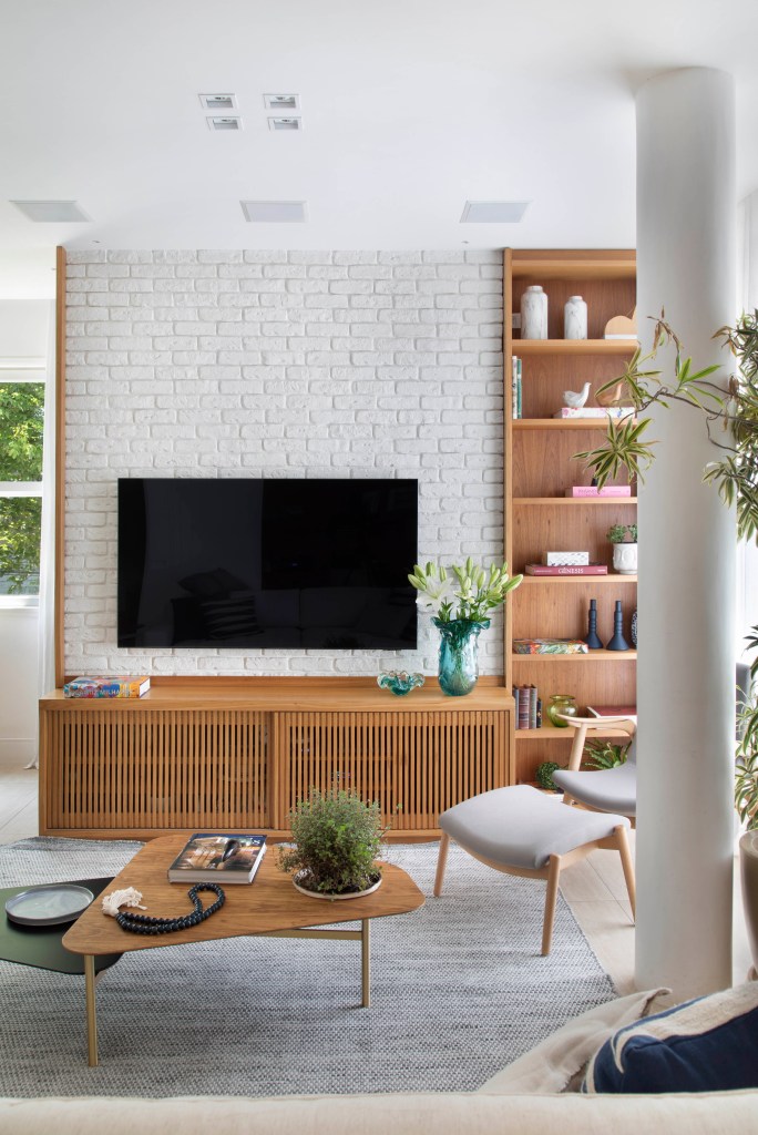 TV em parede com tijolinhos brancos e painel de madeira