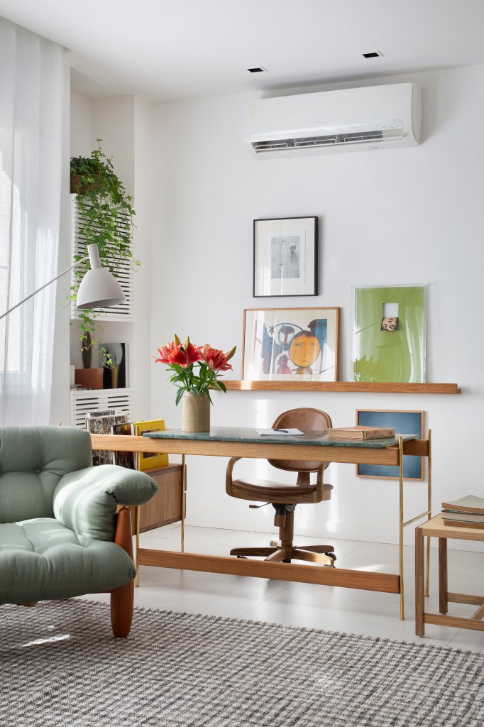 Sala de estar com poltrona verde e home office de madeira