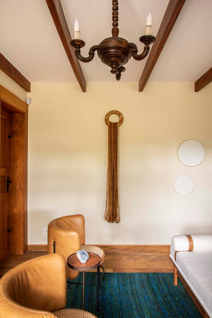 Sala com vigas de madeira no teto e poltronas marrons