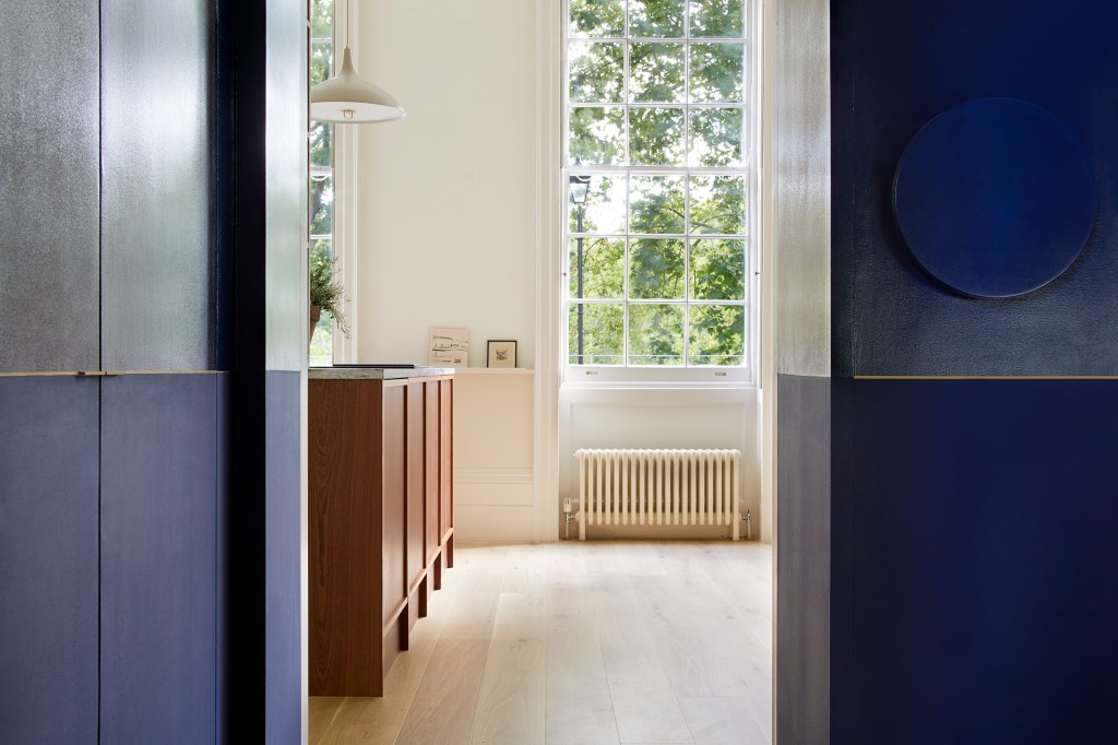 Ambiente com piso de madeira, grande janela de vidro e armário de madeira