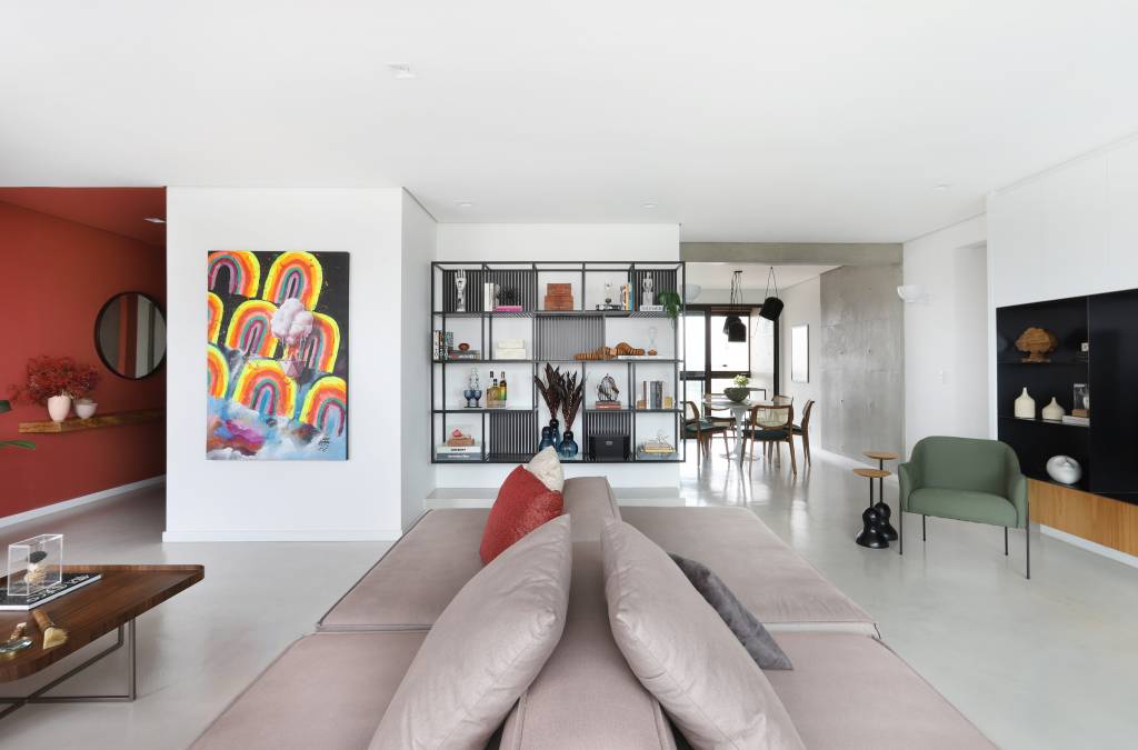 Sala de estar com sofá bege/cinza no meio, obra de arte colorida e estante modular ao fundo