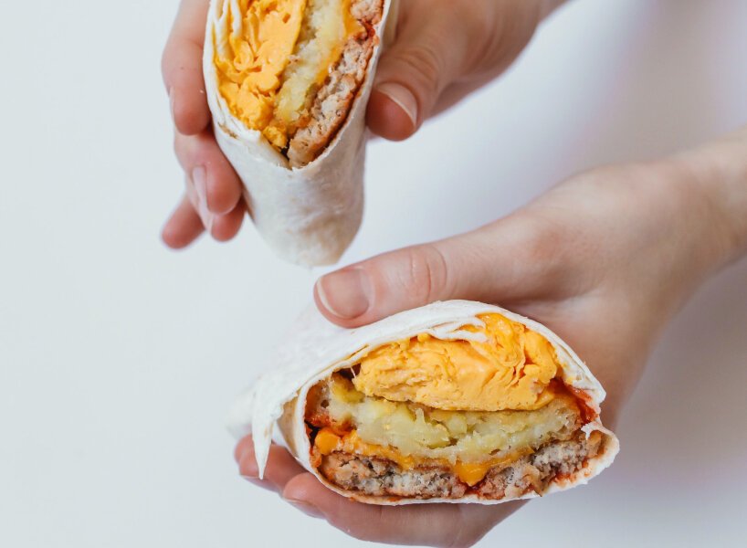 Duas mãos com um burrito bem recheado em cada.