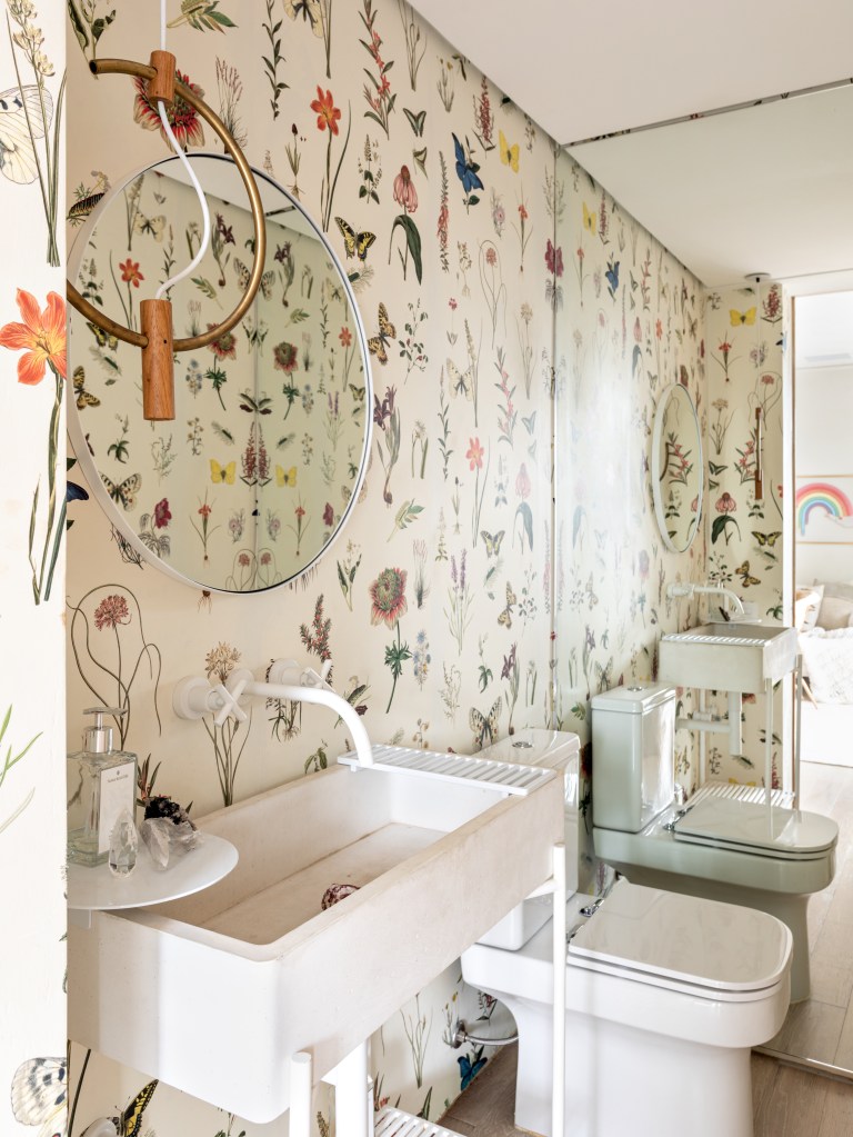 Lavabo com papel de parede botânico; pia; bancada e espelho circular