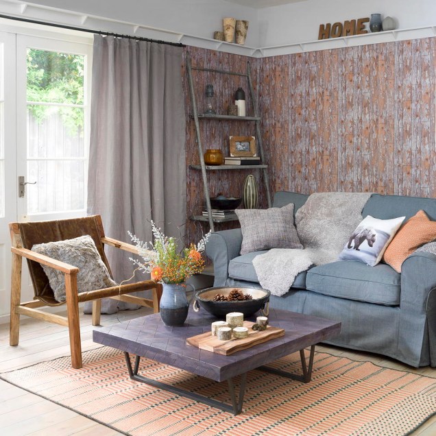 Focus on the sofa in a living room decorated in a rustic style with fur throw and cushions in muted autumn colours.