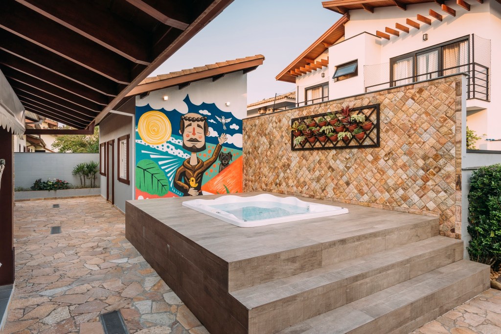 Foto mostra piscina piscina com moldura de alvenaria e acesso por pequena escada. Ao fundo, um grafite mostra São Francisco.