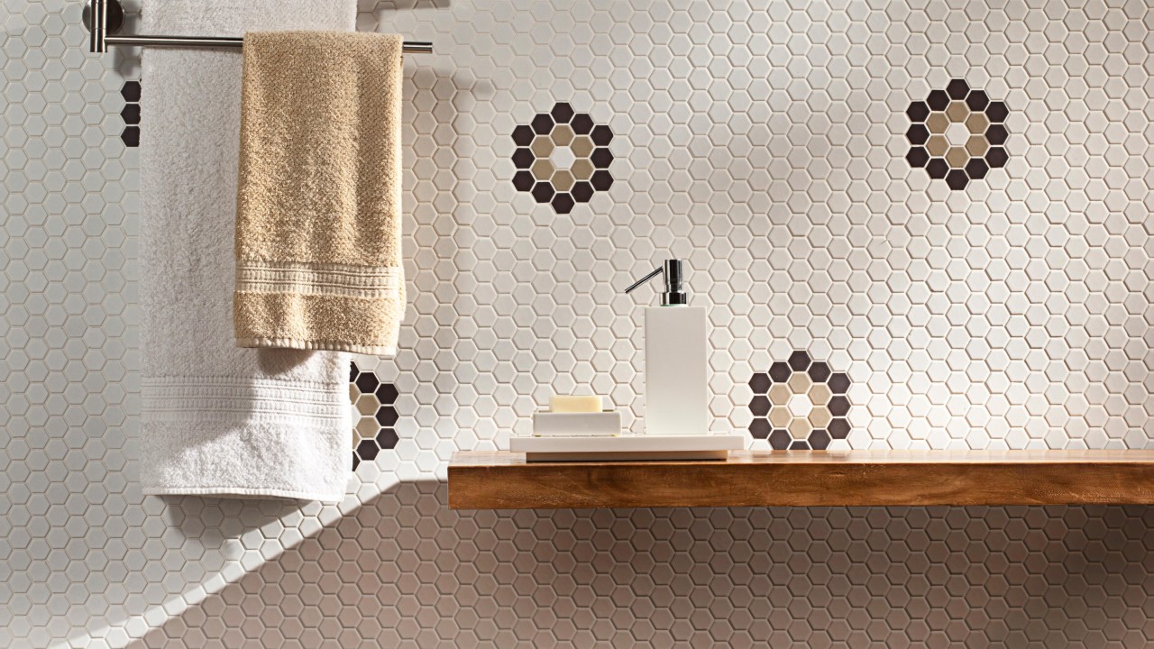 Foto mostra parede de lavabo revestida com pastilhas que receberam detalhe customizado, em que desenhos com outras cores formam um hexágono.