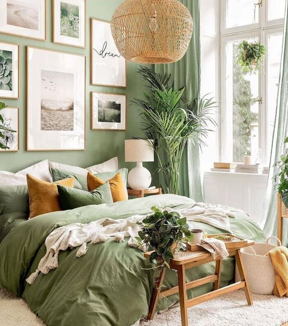 quartos-verde-cabeceira-cama-luminaria-quadros-plantas-olid-homes Quarto com cama de casal com roupa de cama verde e travesseiros verdes e laranjas; quadros na parede; banquinho de madeira com vaso de planta