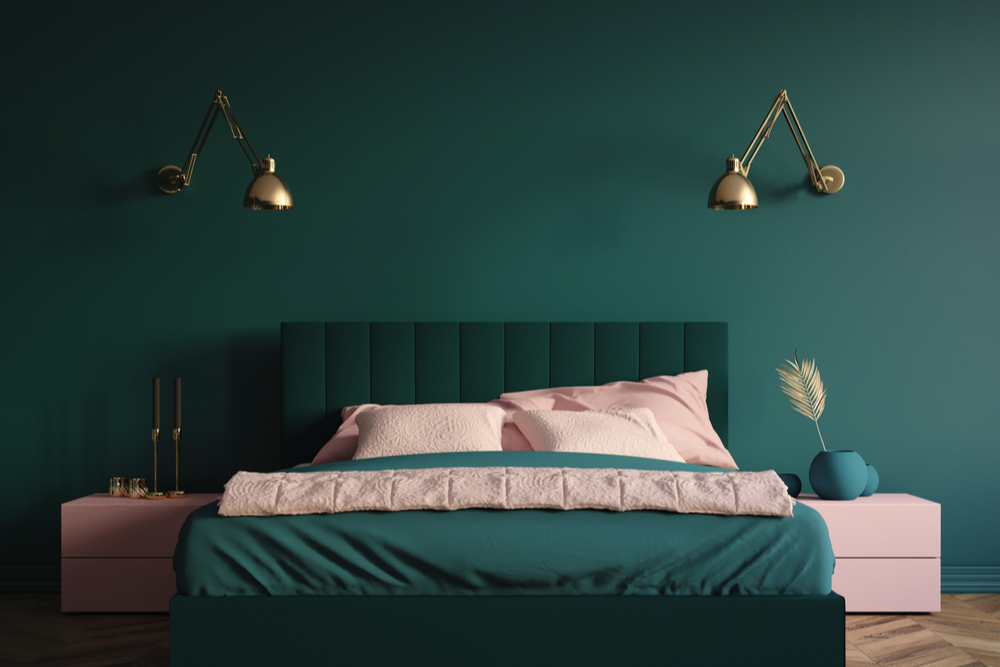 Quarto verde com cama em roupa de cama verde e fronhas rosas.