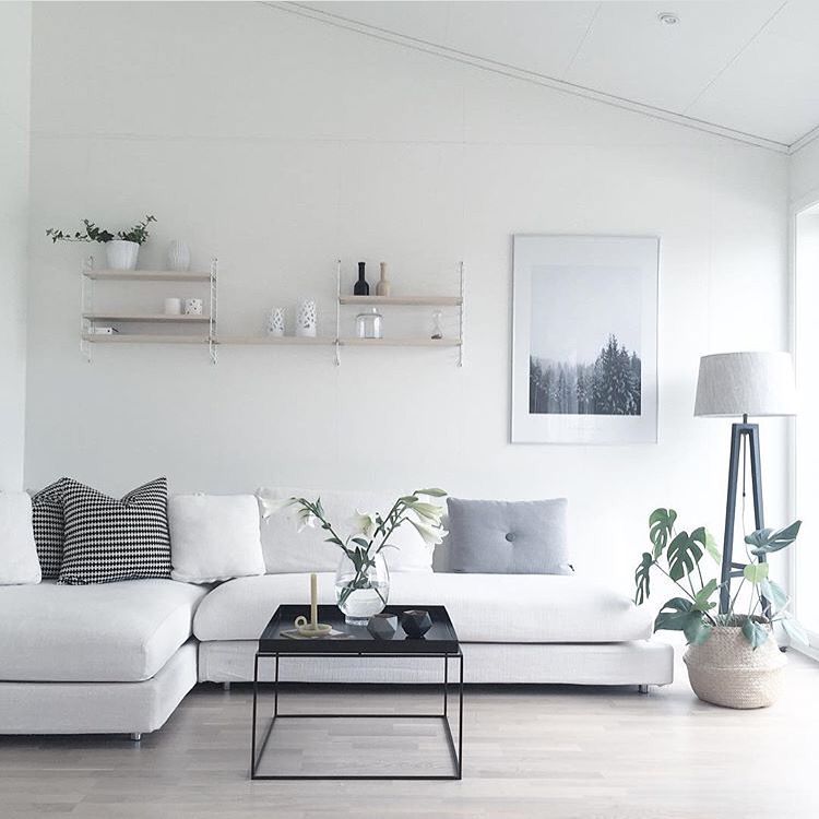 Sala de estar minimalista com sofá branco em L e mesa de centro preta