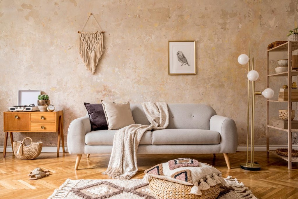 Sala em estilo WabiSabi com sofá cinza, almofadas, mantas e tapete