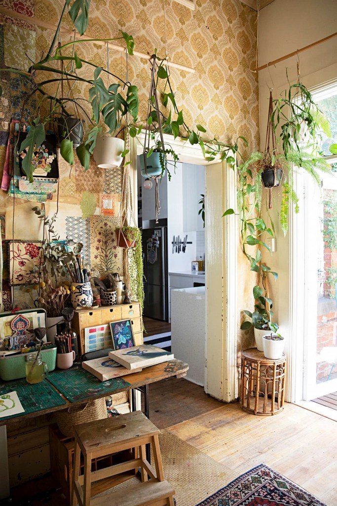 10 home offices estilosos com plantas na decoração Paula Mills Art The Decoist Home office ao lado de uma porta emoldurada por vasos de plantas embutidas na parede.