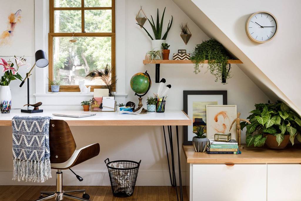 Home office com prateleiras acima da mesa repletas de plantas.