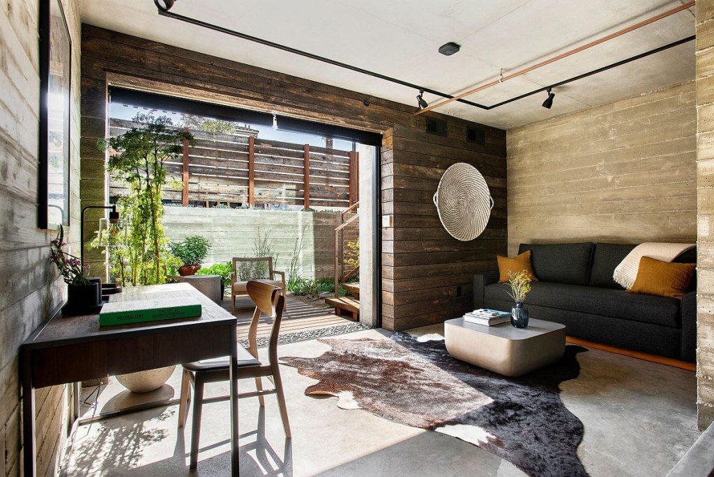 10 home offices estilosos com plantas na decoração The Decoist (3) Home office amplo, rústico, com paredes revestidas por placas de madeira. Da porta para fora é possível ver um jardim repleto de plantas.