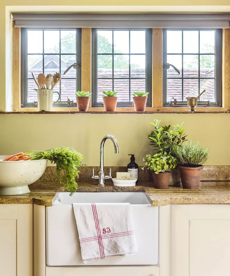 Vasos com mudas de ervas posicionados em janela de cozinha