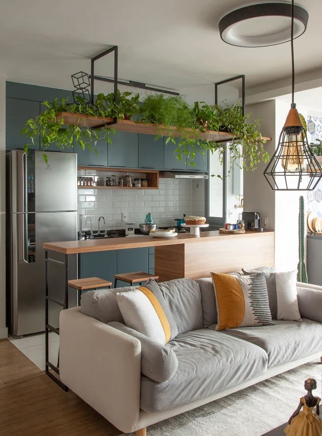 Foto mostra sala de estar e jantar integradas, com prateleira de plantas sobre sofá.