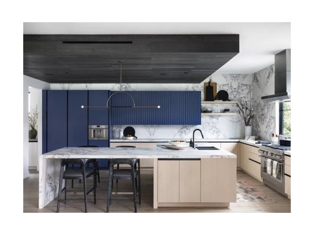 Muitos elementos de design neste exemplo chamam a atenção: o backsplash de mármore que atinge o teto e a ilha de cozinha de grandes dimensões são alguns. Mas a peça principal é o armário azul brilhante que se estende até a despensa e a geladeira.