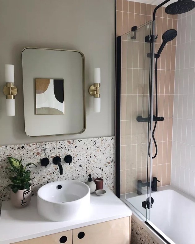 Banheiro com cuba de apoio branca e detalhe em preto combinando com torneiras de parede na cor preta, também usada nos metais da área de banho.