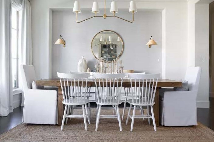Sala de jantar com paredes e cadeiras brancas, contrastando com mesa de madeira escura.