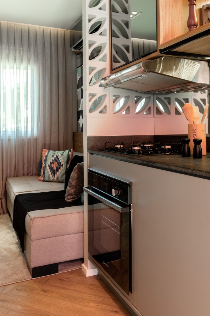 Cozinha e sala de estar integradas, um cobogó faz a divisória entre os ambientes.