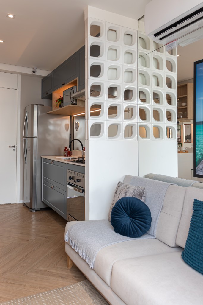 Cozinha e sala de estar integradas, um cobogó faz a divisória entre os ambientes.