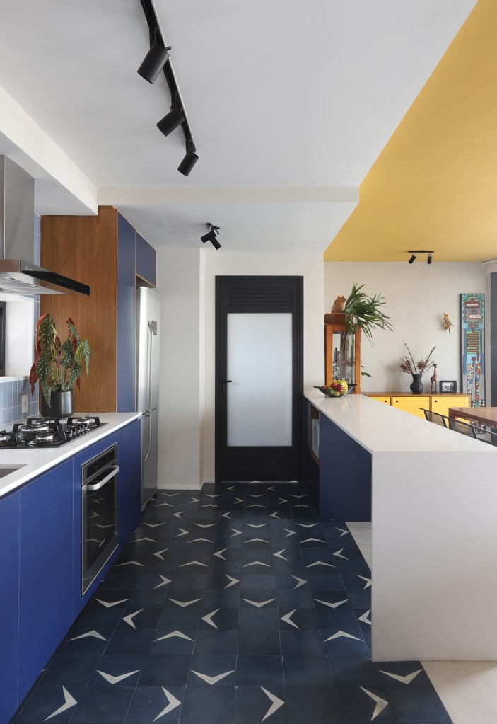 Cozinha integrada com marcenaria azul e piso geométrico