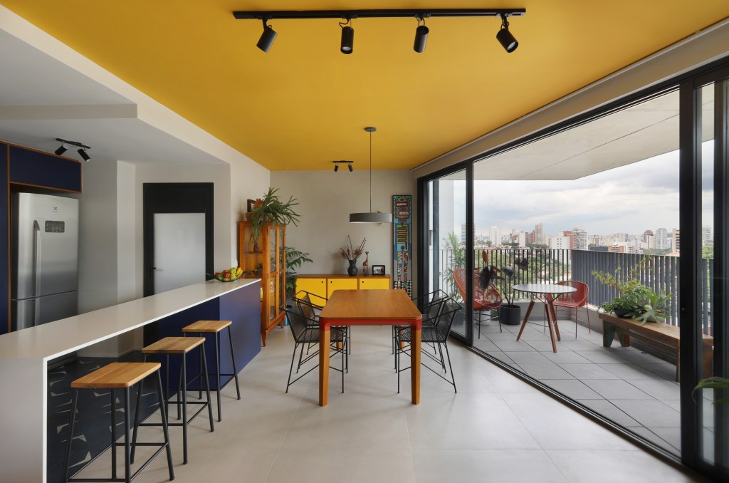 Cozinha integrada com sala com teto colorido amarelo.