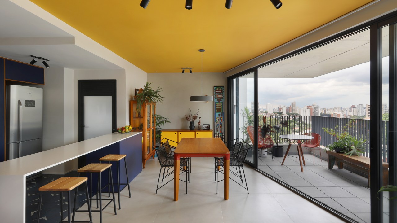 Cozinha integrada com sala com teto colorido amarelo.