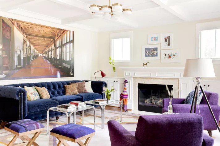 Sala de estar com paredes brancas e móveis em cores de destaque, azul marinho e roxo.