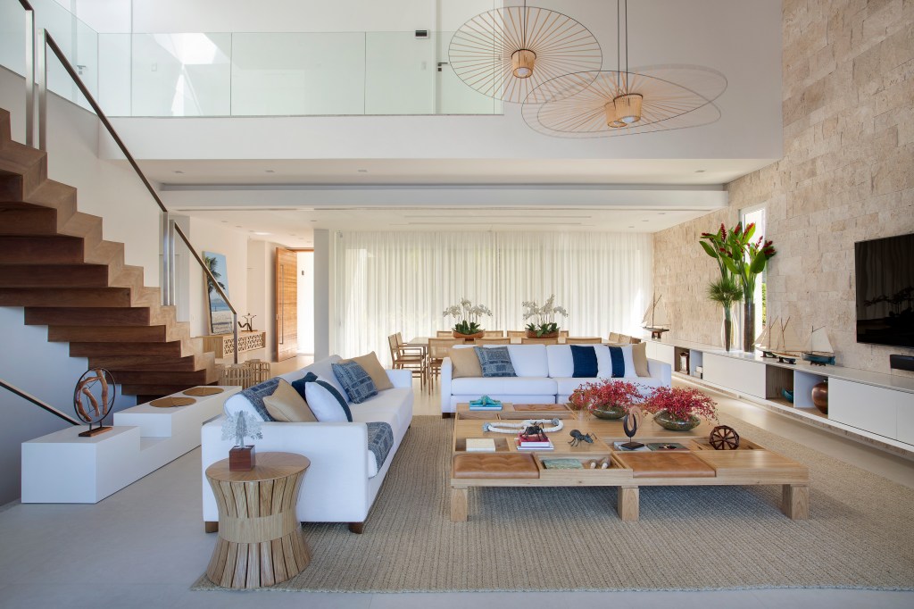 Sala de estar com tv; sofás brancos e mesas de centro em madeira