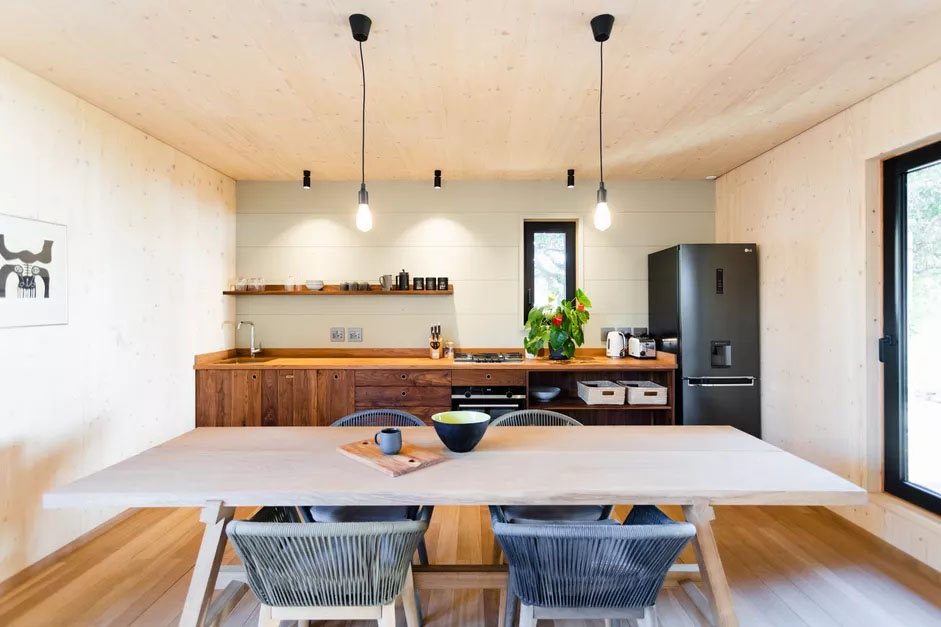 Cozinha de uma parede só com uma longa mesa de madeira.
