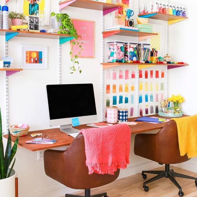 Home office com duas cadeiras em couro; paredes com prateleiras cobertas de post-its coloridos