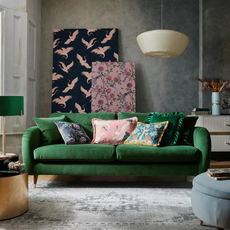 ideias-parede-sofa0 Sofá de veludo verde em frente a uma alta parede, onde estão encostados dois grandes quadros.