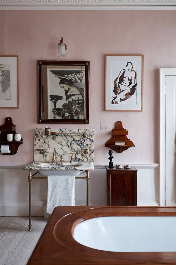 imewashed-walls-a-tub-a-free-standing-sink-wooden-shelves-and-a-gallery-wall Banheiro com uma parede repleta de quadros.